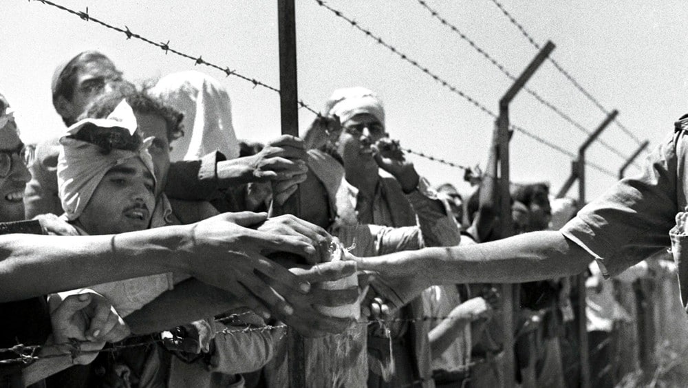 Arabiske fanger - Arabiske fanger blir tildelt mat av en israelsk vakt gjennom et piggtrådgjerde. David Ben Gurion erklærte Israel for selvstendig 14. mai 1948. Egypt, Syria, Jordan og det fremadvoksende Irak angrep Israel dagen etter. - Foto: HO / REUTERS