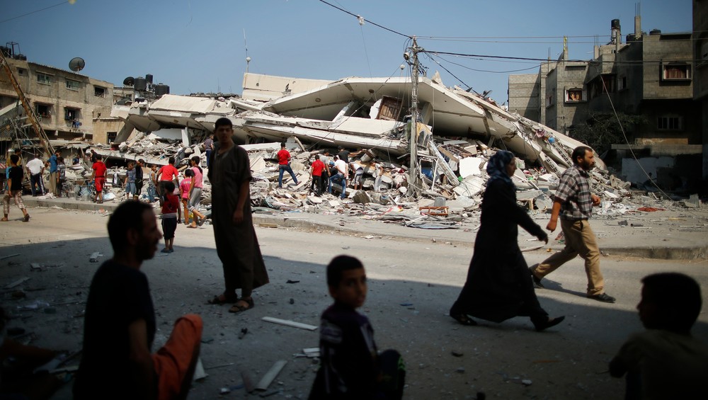 Barn foran ødelagt bygning i Gaza by - Deler av bygningsmassen på Gazastripen er bombet og gjenoppbygd flere ganger. - Foto: MOHAMMED SALEM / Reuters