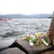 Blomster er lagt ned for å minnes de drepte, på vannet utenfor bryggen søkes det fortsatt etter savnede.