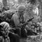 1966: Sør-vietnamesiske barn stirrer på en amerikansk soldat mens de holder seg fast i mødrene sine. De gjemmer seg for skudd fra Vietcong-soldater. 