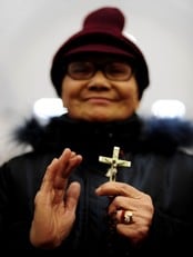 En kinesisk kvinne holder et kors under en julegudstjeneste i en katolsk kirke i Wuhan (Foto: STR/Afp)