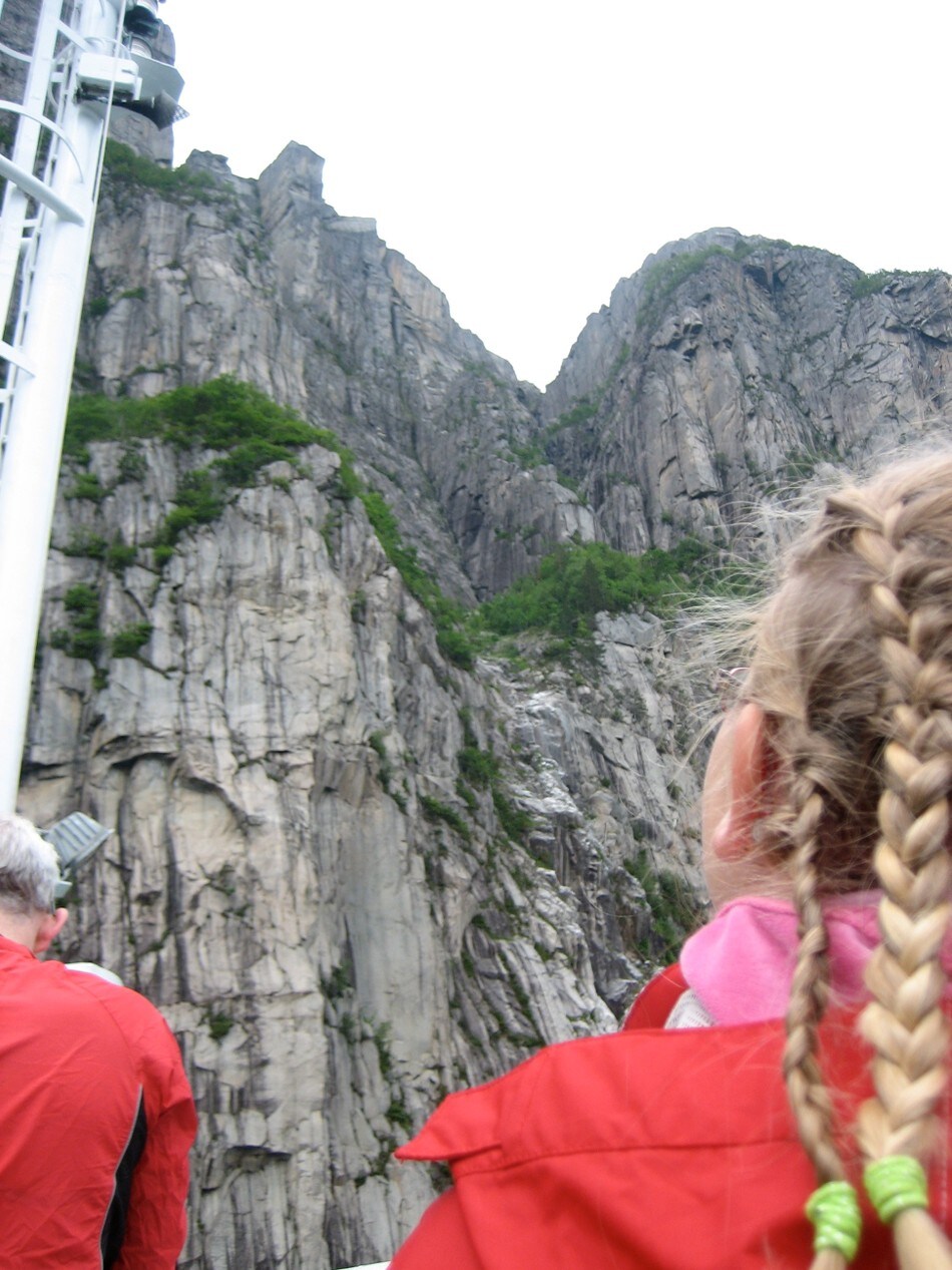 Sted: Fergen fra Preikestolen inn til Kjerag
Motiv: Maia står å ser opp på preikestolen hun dagen før satt på....og det ble et veldig spennende bilde sett gjennom barneøyne.... [lena@frknilsen.no, 41545683]