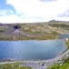 Rondvassbu i Rondane. Hytta synes godt til høyre og Jutulhogget til venstre. Besøkende sitter ute i solveggen og nyter dagen.