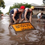 Folk i forstaden Westend i Brisbane bruker et skilt til å skuffe vekk gjørme (Foto: TIM WIMBORNE/Reuters) Folk i forstaden Westend i Brisbane bruker et skilt til å skuffe vekk gjørme (Foto: TIM WIMBORNE/Reuters)
