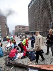 Skadde hjelpes på Einar Gerhardsens plass i regjeringskvartalet etter bomben (Foto: Holm, Morten/Scanpix) Skadde hjelpes på Einar Gerhardsens plass i regjeringskvartalet etter bomben (Foto: Holm, Morten/Scanpix)