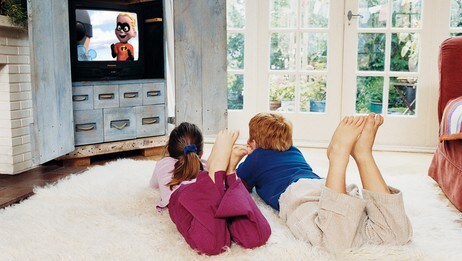 Barn ligger foran TV-en Barn ligger foran TV-en