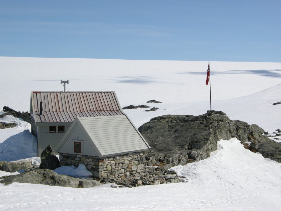 Drømmedag ved Fonnabu. Ikke et vindpust. Her ser vi steinbuen og gamlehytten og breen bak.