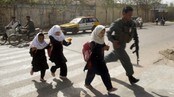Politimann følger jenter på skolen i Herat (Foto: R. Shirmohammad/Scanpix/AP)