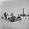 Teltleir med sleder hunder og annet utstyr samt et depot (merket med flagg) i bakgrunnen ved siden av teltet. Bildet er antakelig fra første depottur til 80 grader sørlige bredde, Antarktis, 1911.