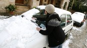 En kvinne skraper snø av bilen sin i Valldemossa, Mallorca