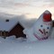 Sliten snømann på Bugøynes med vinterlyset i bakgrunnen.