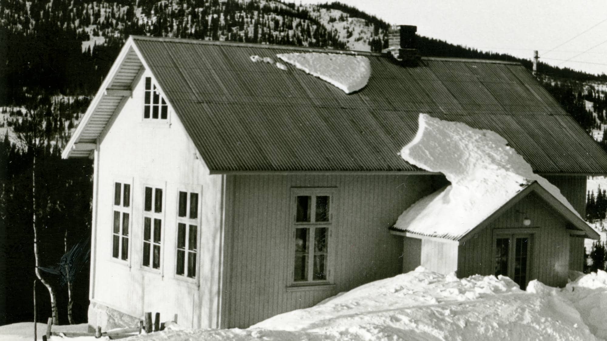 En gammel skolebygning med snø på taket og rundt.