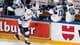 Anthony Anex / Keystone,NTB Ishockeyspillere i hvite drakt med norsk flagg feirer på isen. En spiller med nummer 49 på ryggen går forbi reklamebandet. Andre spillere sitter på benken i bakgrunnen. Spillerne har hjelmer og hansker. (Bildebeskrivelsen er laget av en KI-tjeneste)