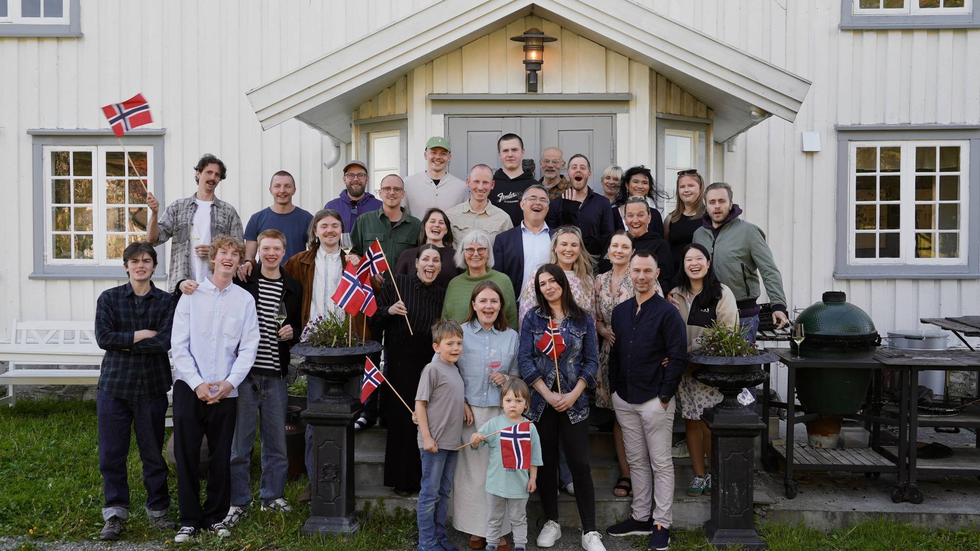En gjeng mennesker med norske flagg står utenfor Kvitnes Gård etter at de fikk Michelin-stjerne. 