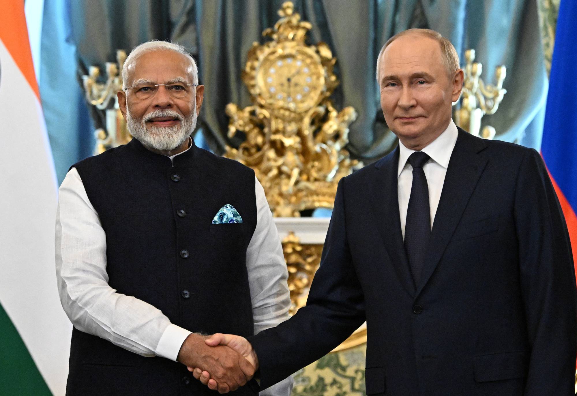 Indias statsminister Narendra Modi og Russlands president Vladimir Putin håndhilser. Bak dem henger flaggene til India og Russland. (Bildebeskrivelsen er laget av en KI-tjeneste)