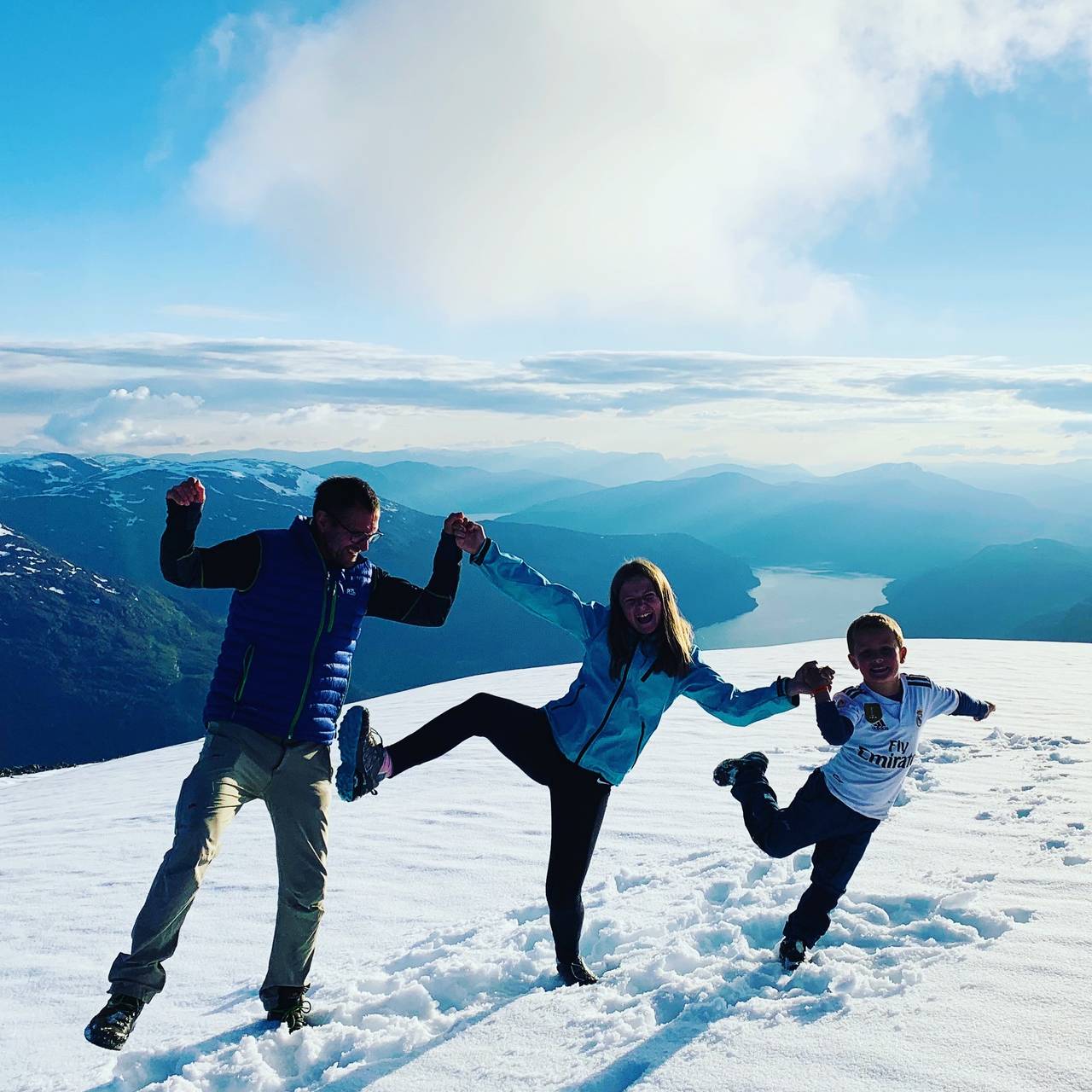 En familie danser på toppen av Skåla.
