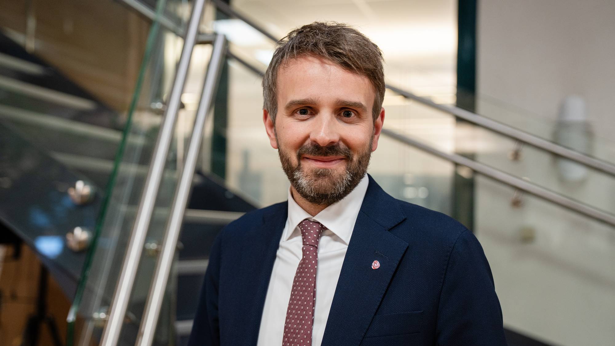 Jan Christian Vestre står inne på marienlyst og ser i kamera. Han har mørkeblå dress, hvit skjorte, og rødt og hvitt slips. 