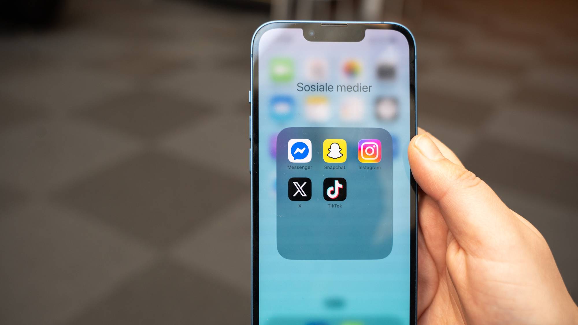 Illustrasjonsbilde av sosiale medier. Bildet viser noen som holder en mobil. På skjermen er det bilde av flere sosiale medier-plattformer.