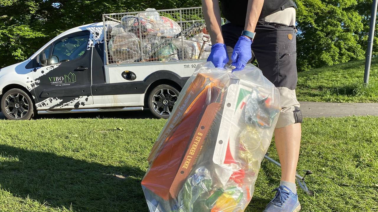 En person knyter sammen en sekk med søppel i parken på Sankthaugen