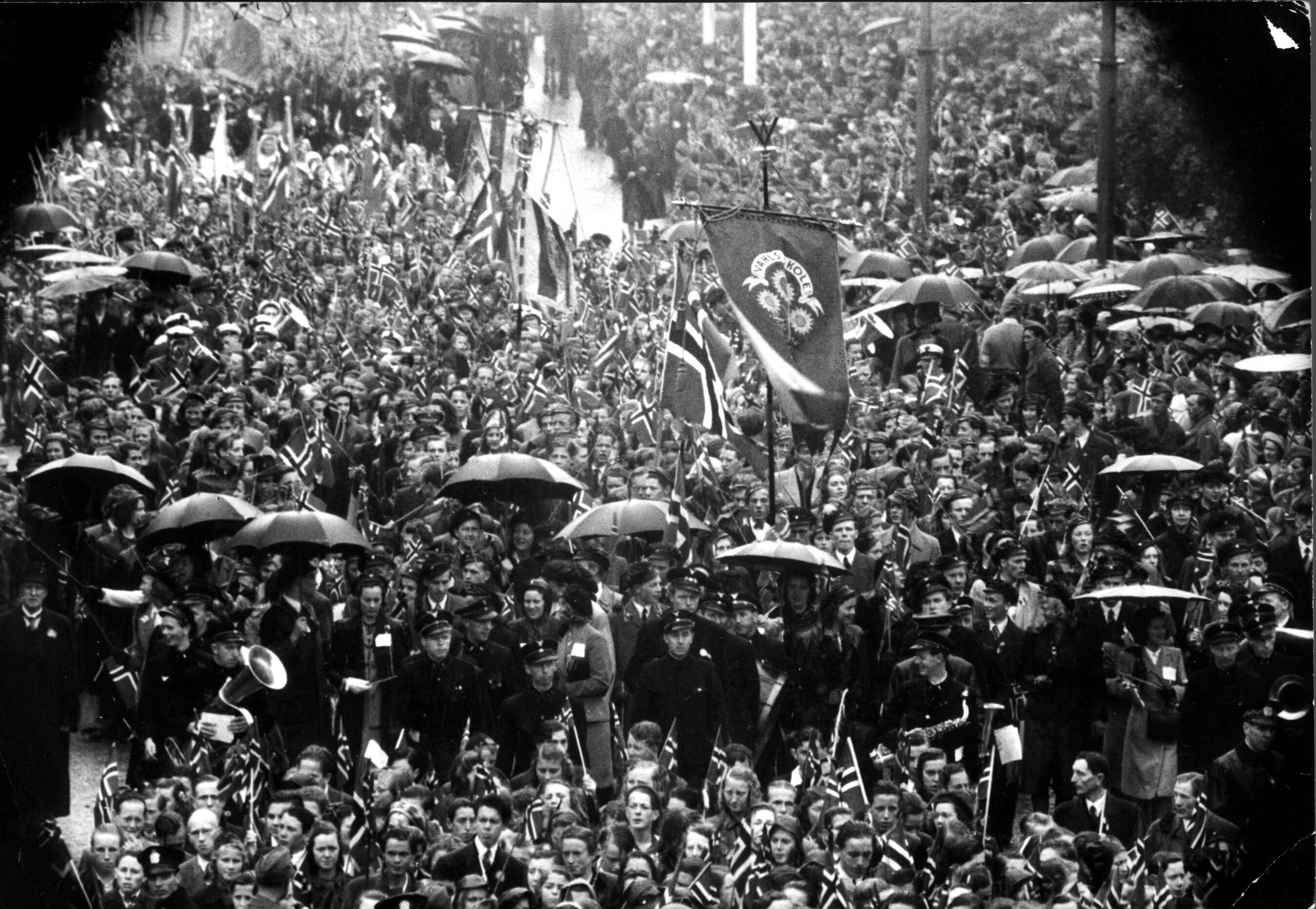 17.mai -feiring Oslo 1945. Regn la ingen demper på festlighetene under den første feiringen av nasjonaldagen etter krigen. Her folkemassen som deltok i festmøtet på Rådhusplassen. Vestbanen i bakgrunnen.