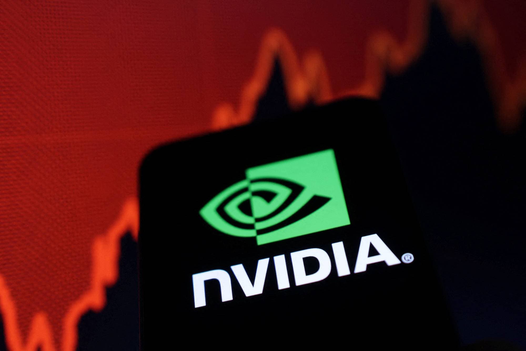 Et smarttelefon-skjerm viser Nvidia-logoen foran en graf med fallende kurver i rødt. Grafen indikerer en nedgang i aksjekursen. Bildet illustrerer mulige økonomiske utfordringer for selskapet. Ingen personer er synlige i bildet. (Bildebeskrivelsen er laget av en KI-tjeneste)