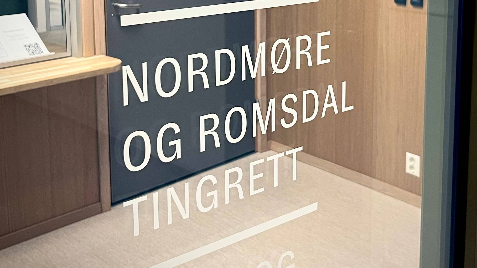 Ei dør med tekst som viser "Frostating lagmannsrett, Nordmøre og Romsdal tingrett". På døren er det et kongerikets våpenskjold. Ved siden av døren er det en lukket luke med en informasjonsplakat. 