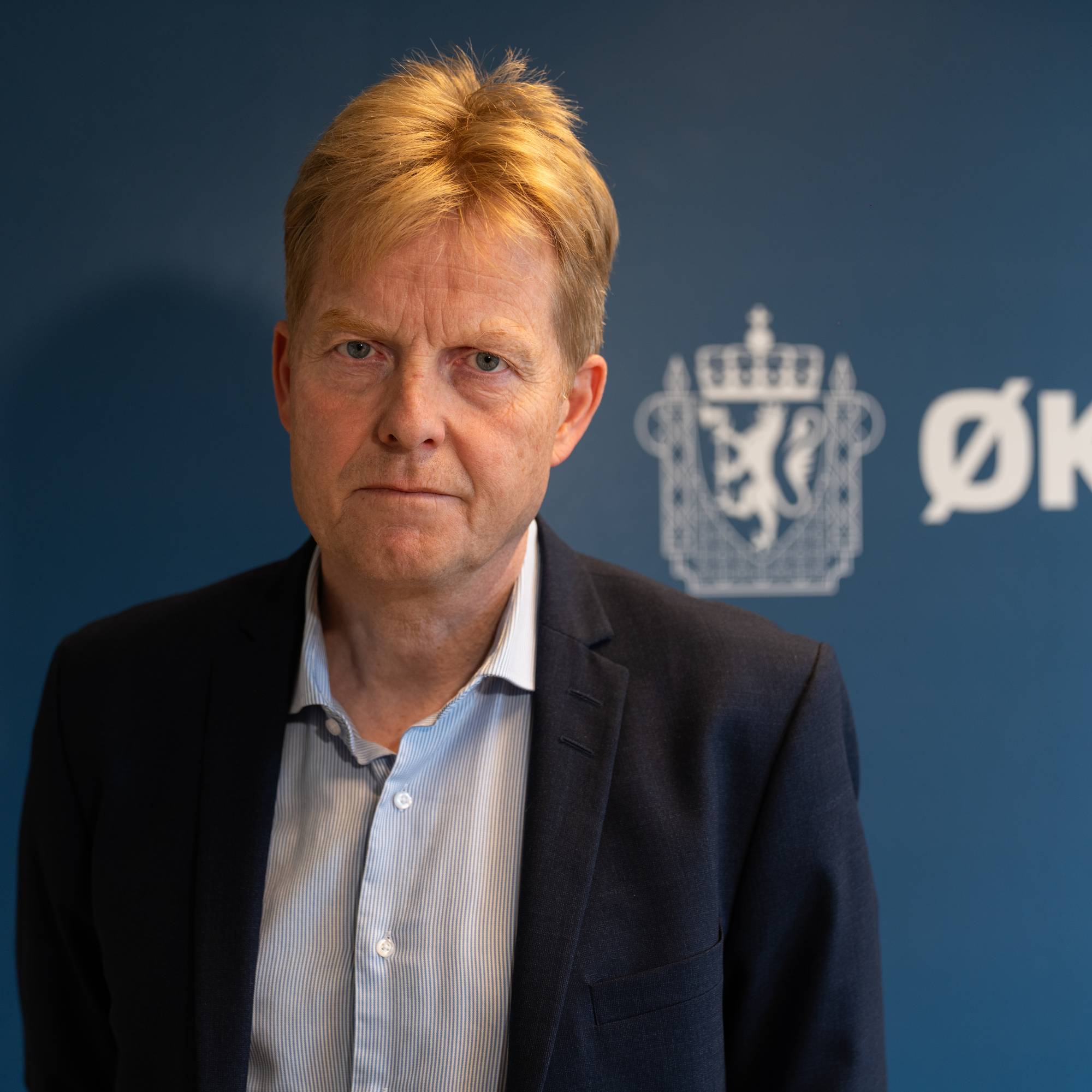 Pål Lønseth fotografert foran Økokrims logo. (Bildebeskrivelsen er laget av en KI-tjeneste)