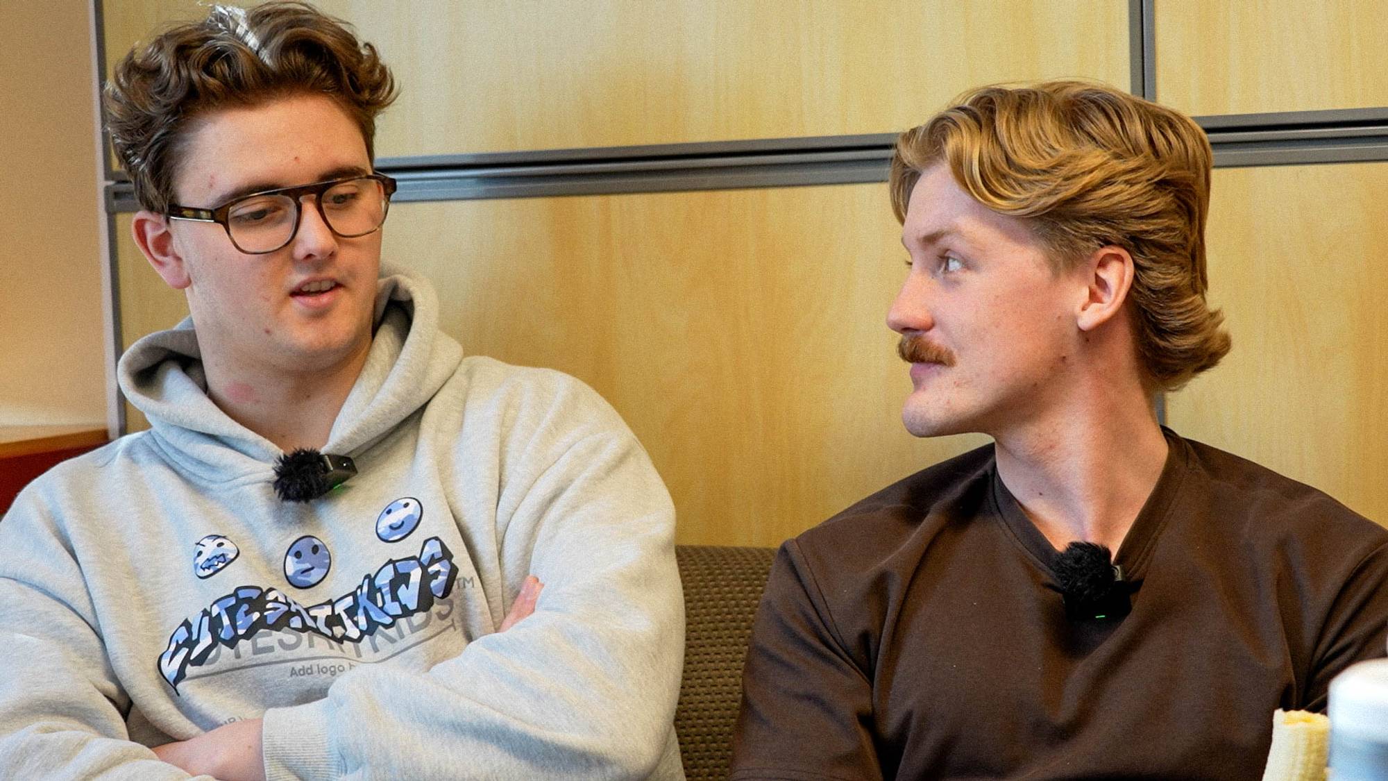 To unge menn snakker sammen mens de sitter i en sofa