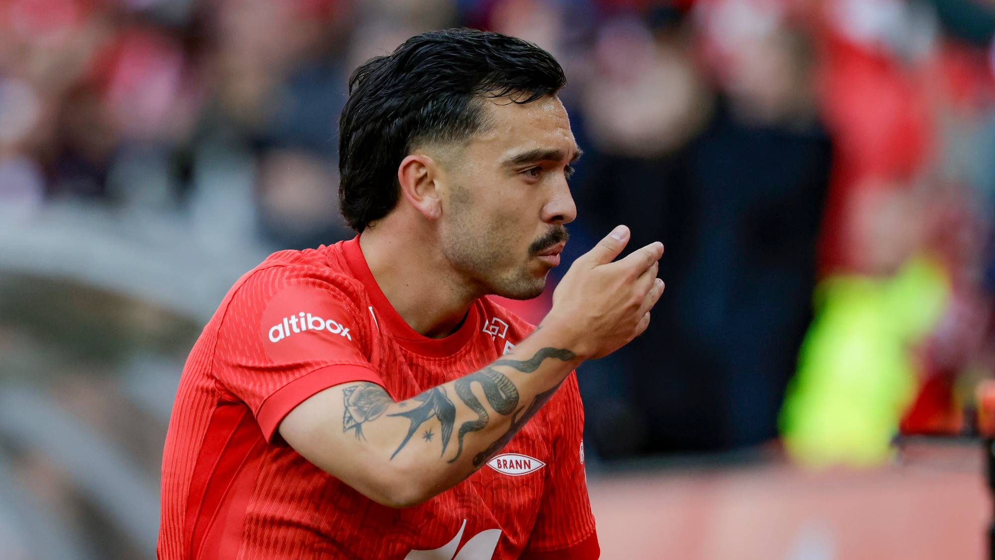Brann-spiller Joachim Soltvedt i rød drakt på fotballbane. (Bildebeskrivelsen er laget av en KI-tjeneste)