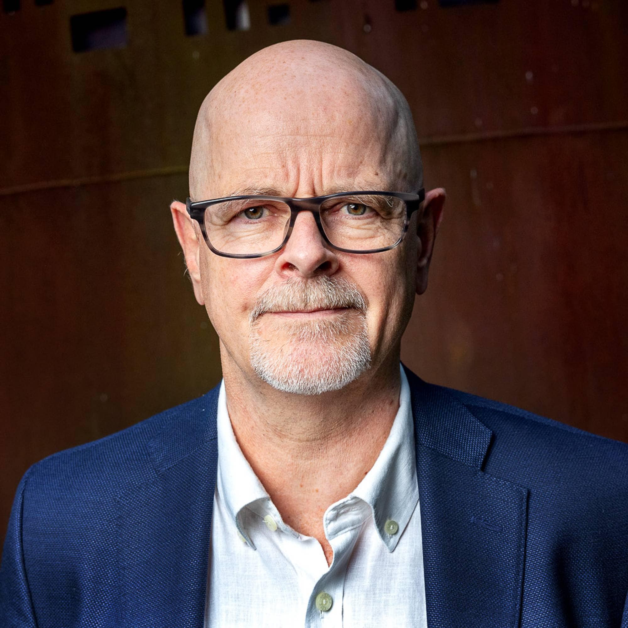 en mann med briller foran en bygning