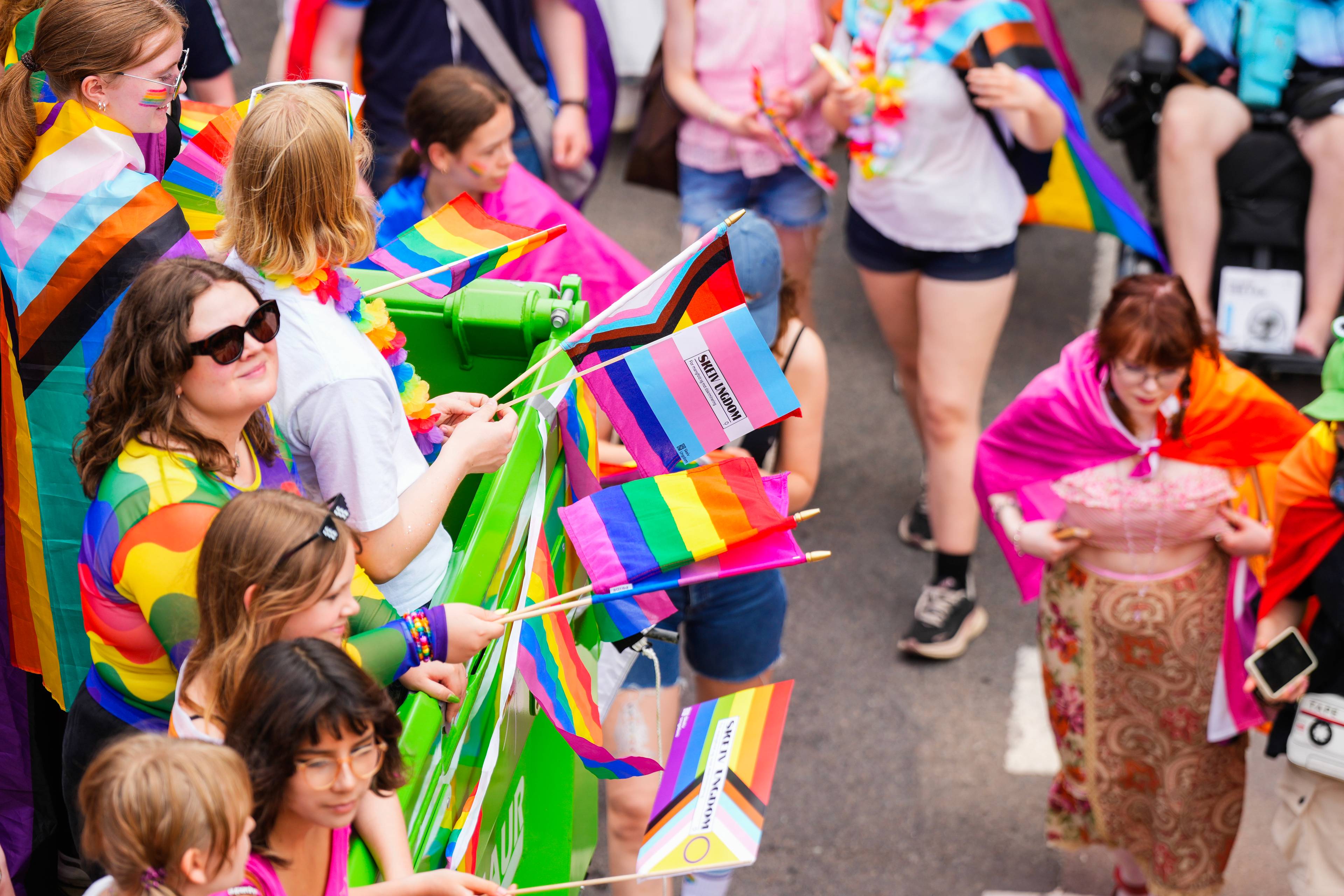 Folk i Pride-parade med regnbueflagg og fargerike klær. (Bildebeskrivelsen er laget av en KI-tjeneste)