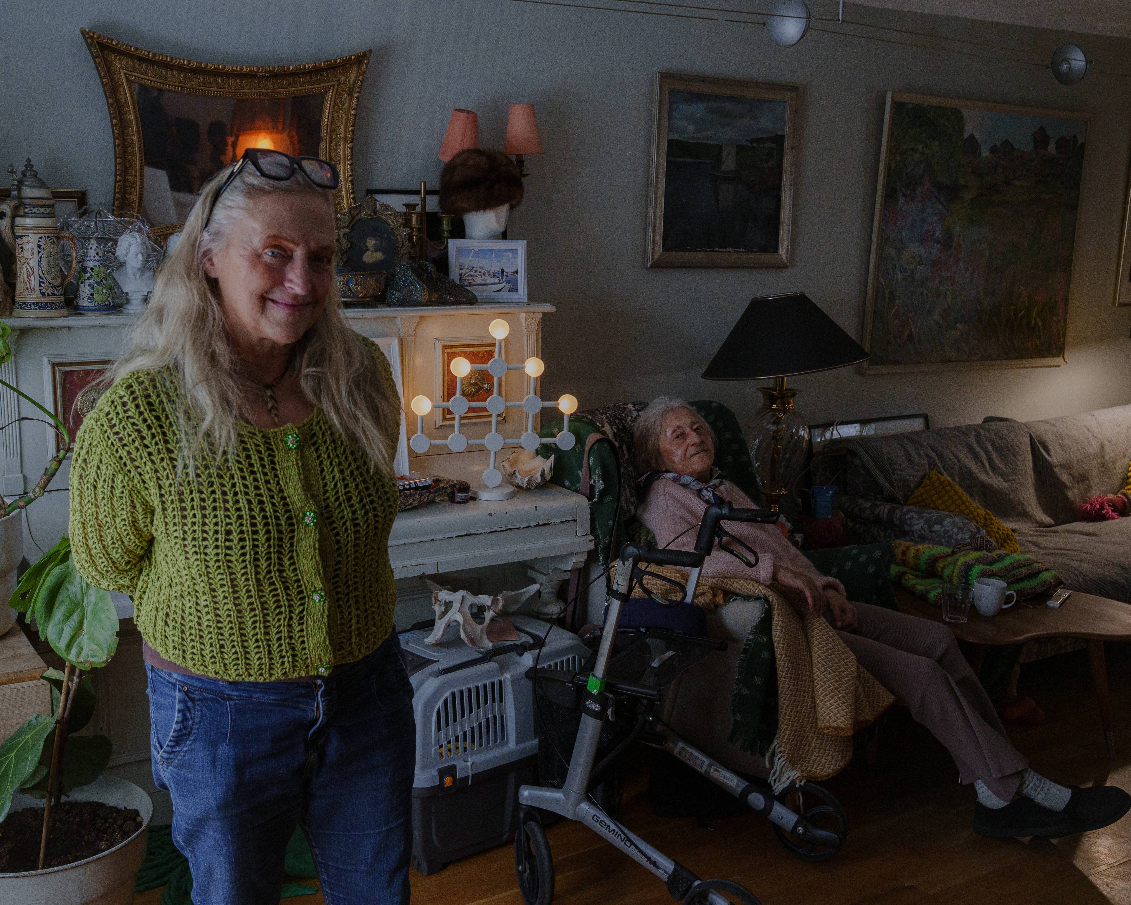 Edith og Magdalena poserer for kamera. Magdalena sitter i lenestolen sin, mens Edith står litt foran og til siden