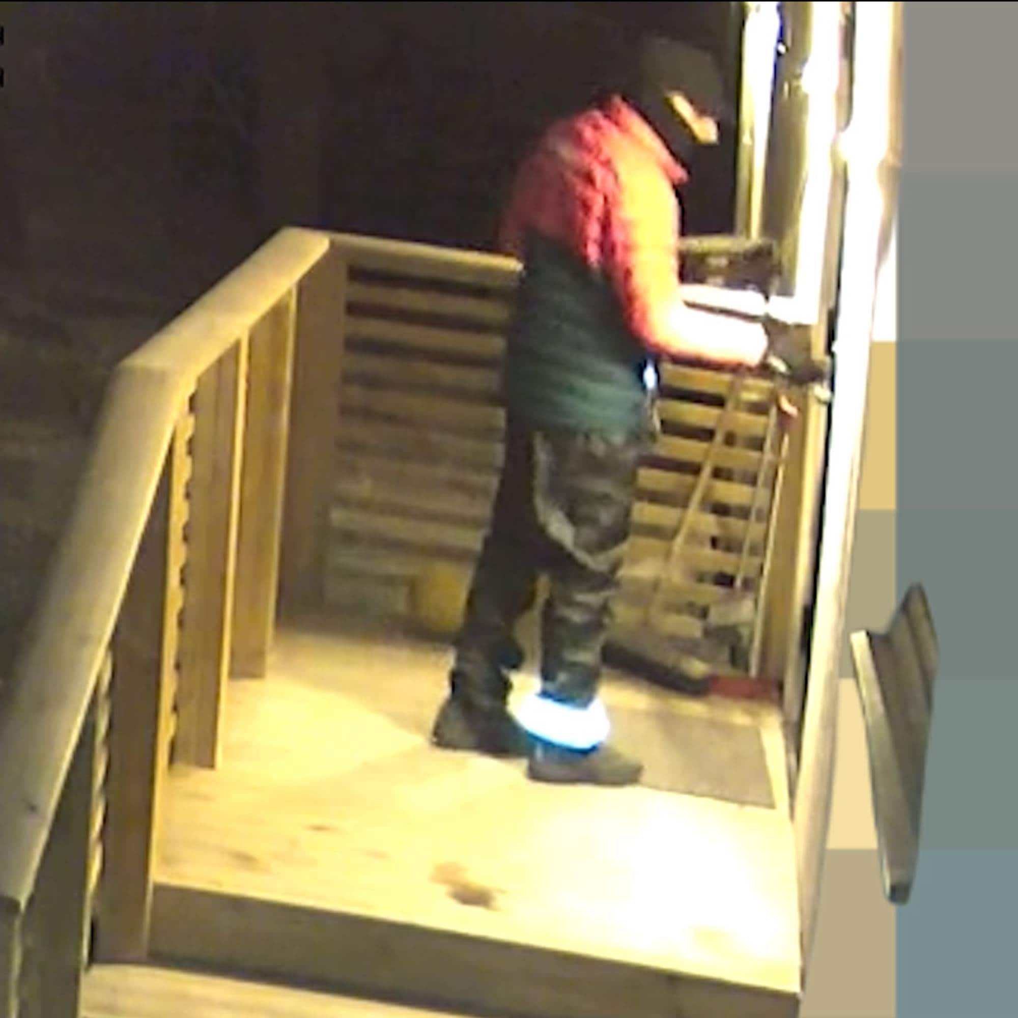 En maskert person med caps ringer på en dørklokke til et hus.