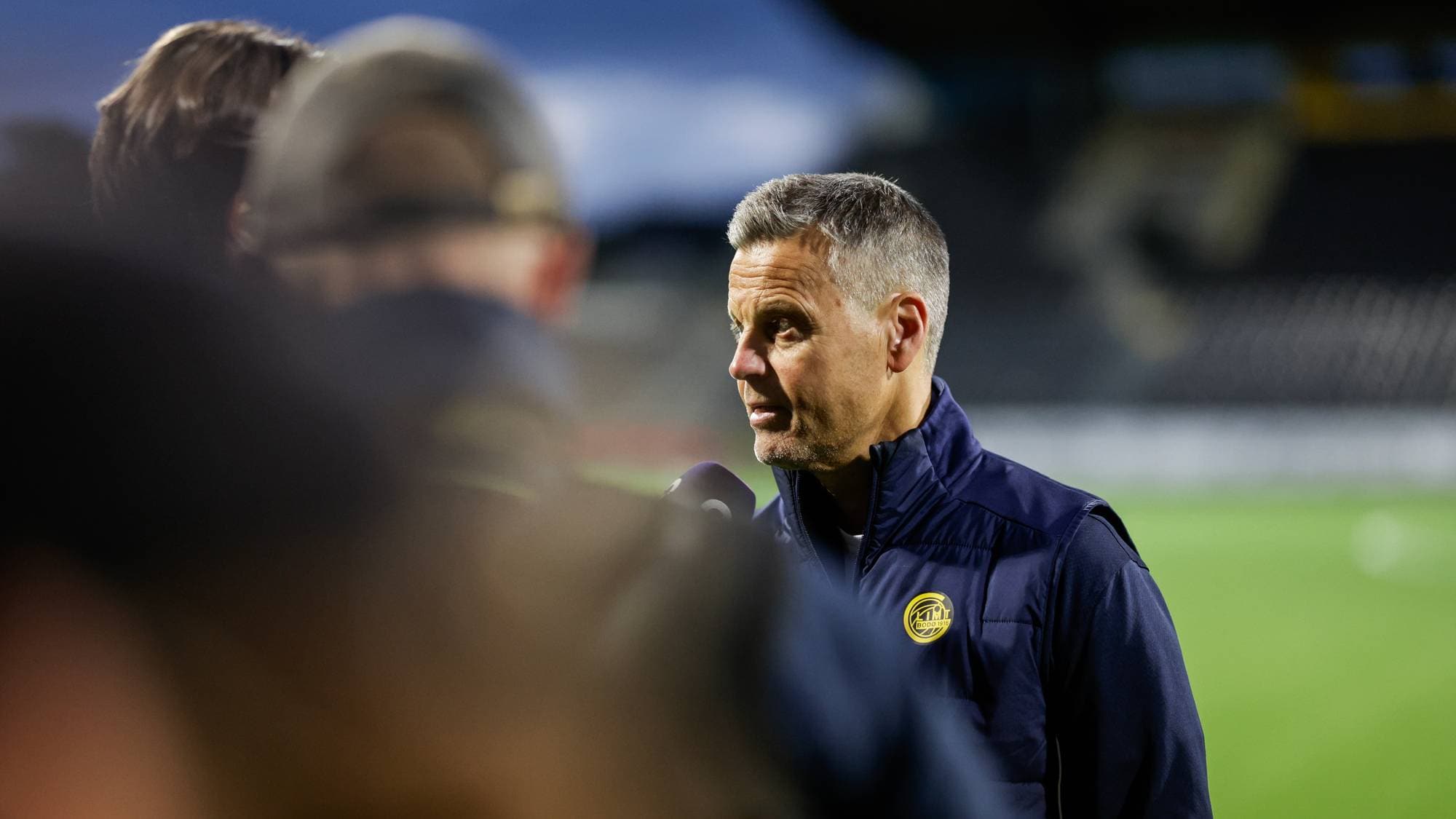 Fotballtrener Kjetil Knutsen blir intervjuet på sidelinjen på en fotballstadion. (Bildebeskrivelsen er laget av en KI-tjeneste)