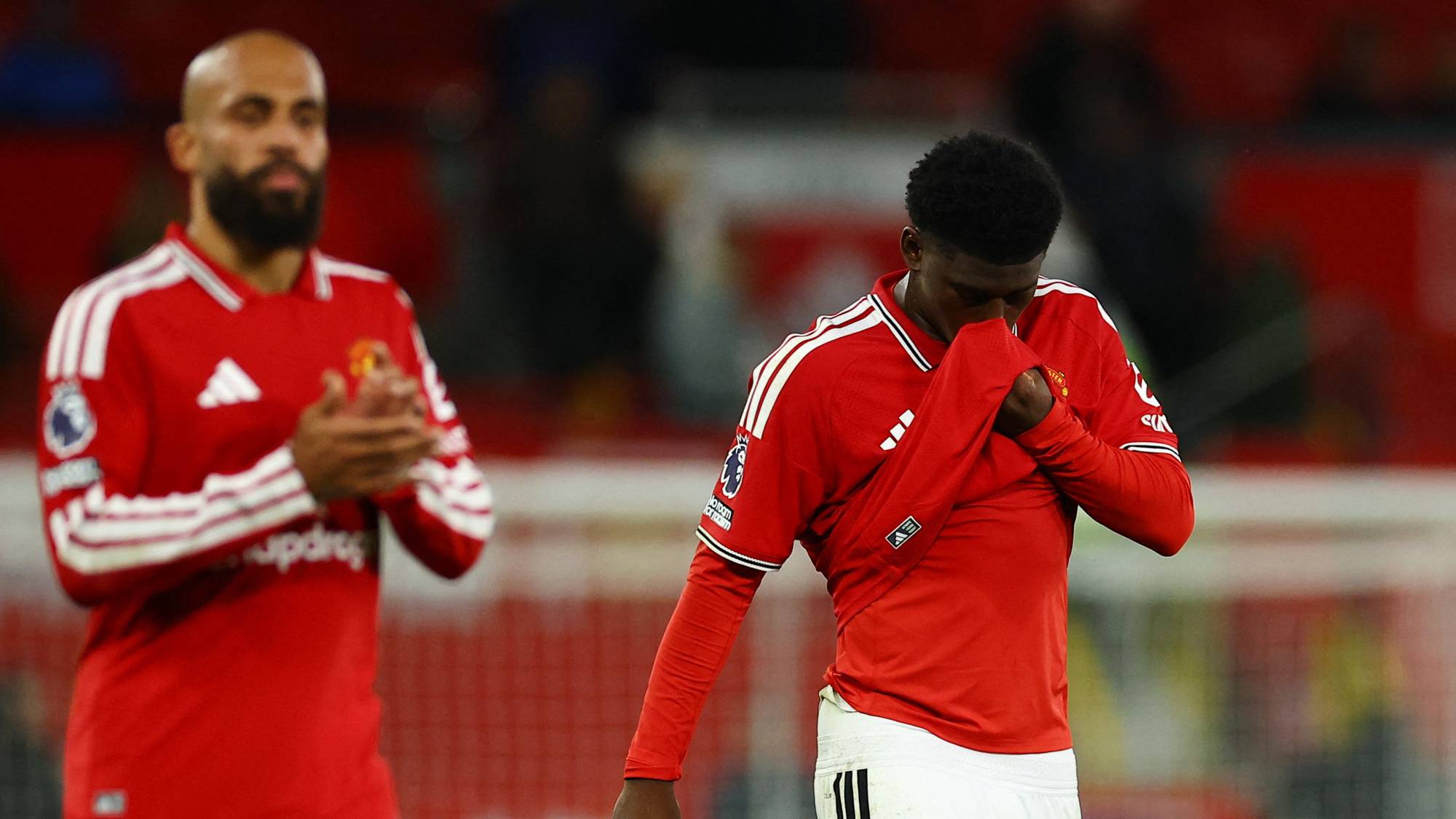 Manchester United-spillere på banen. Én spiller holder drakten over ansiktet, mens en annen klapper. (Bildebeskrivelsen er laget av en KI-tjeneste)