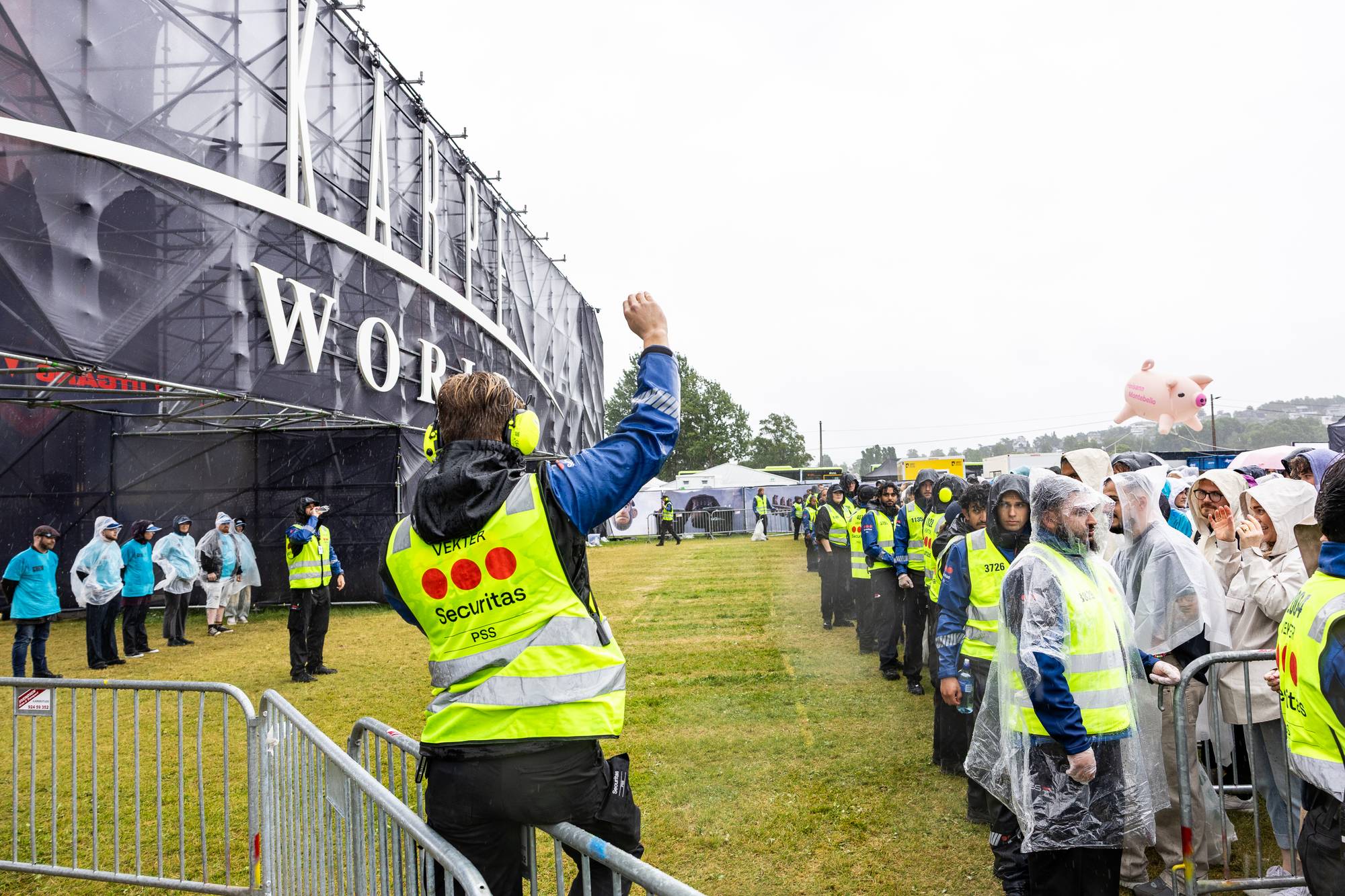 Vekter i gul refleksvest dirigerer publikum ved en inngang til en Karpe-konsert. (Bildebeskrivelsen er laget av en KI-tjeneste)