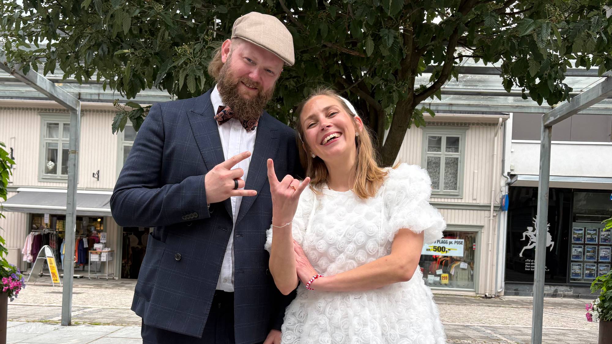Brudepar står foran et tre og viser djevelhorn-tegnet