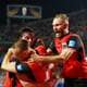Phil Noble / REUTERS,NTB Østerrikske fotballspillere i røde drakter feirer mål ved å klemme hverandre på banen. (Bildebeskrivelsen er laget av en KI-tjeneste)