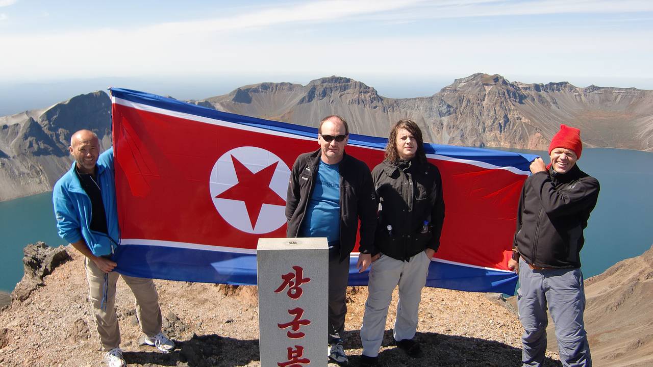 Fire menn med det Nord-Koreanske flagget på toppen av Nord-Koreas høgaste fjell, Paektu-san.