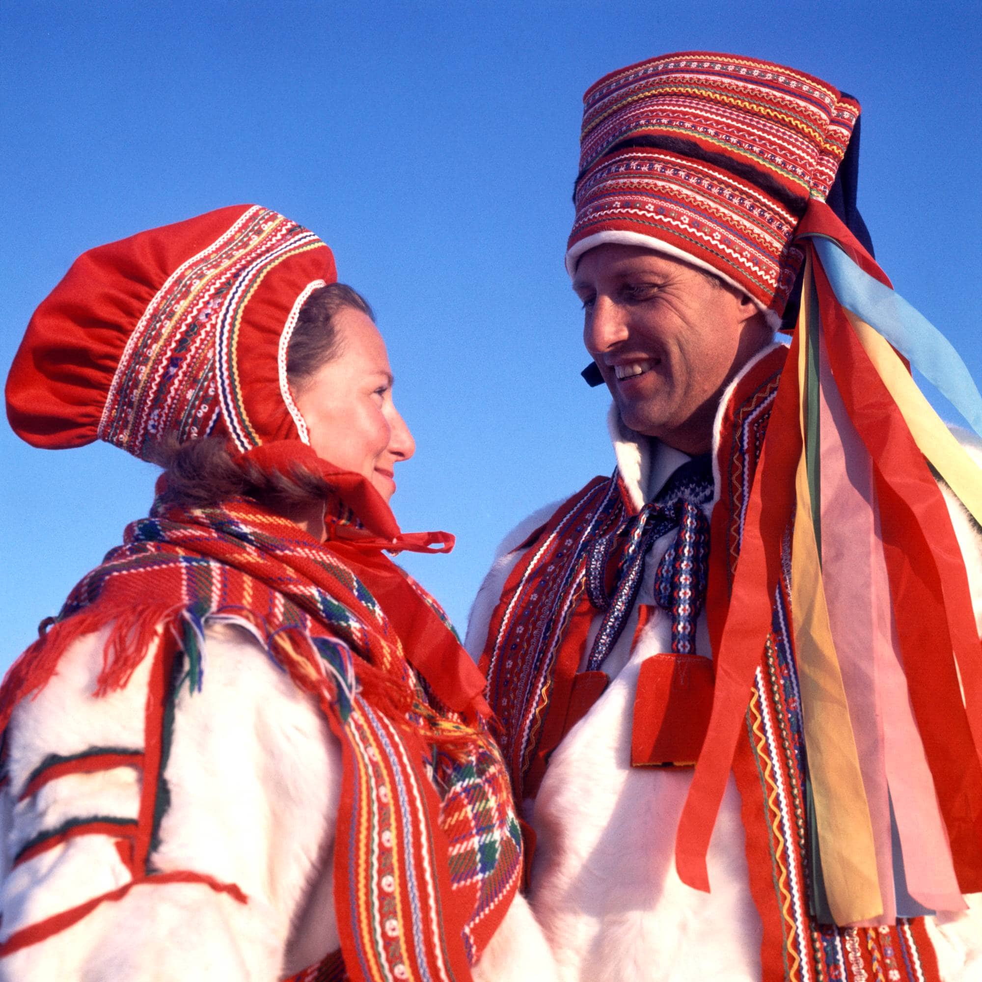 Kronprins Harald og kronprinsesse Sonja i samedrakter under besøk i Karasjok i 1969, de smiler og ser på hverandre.