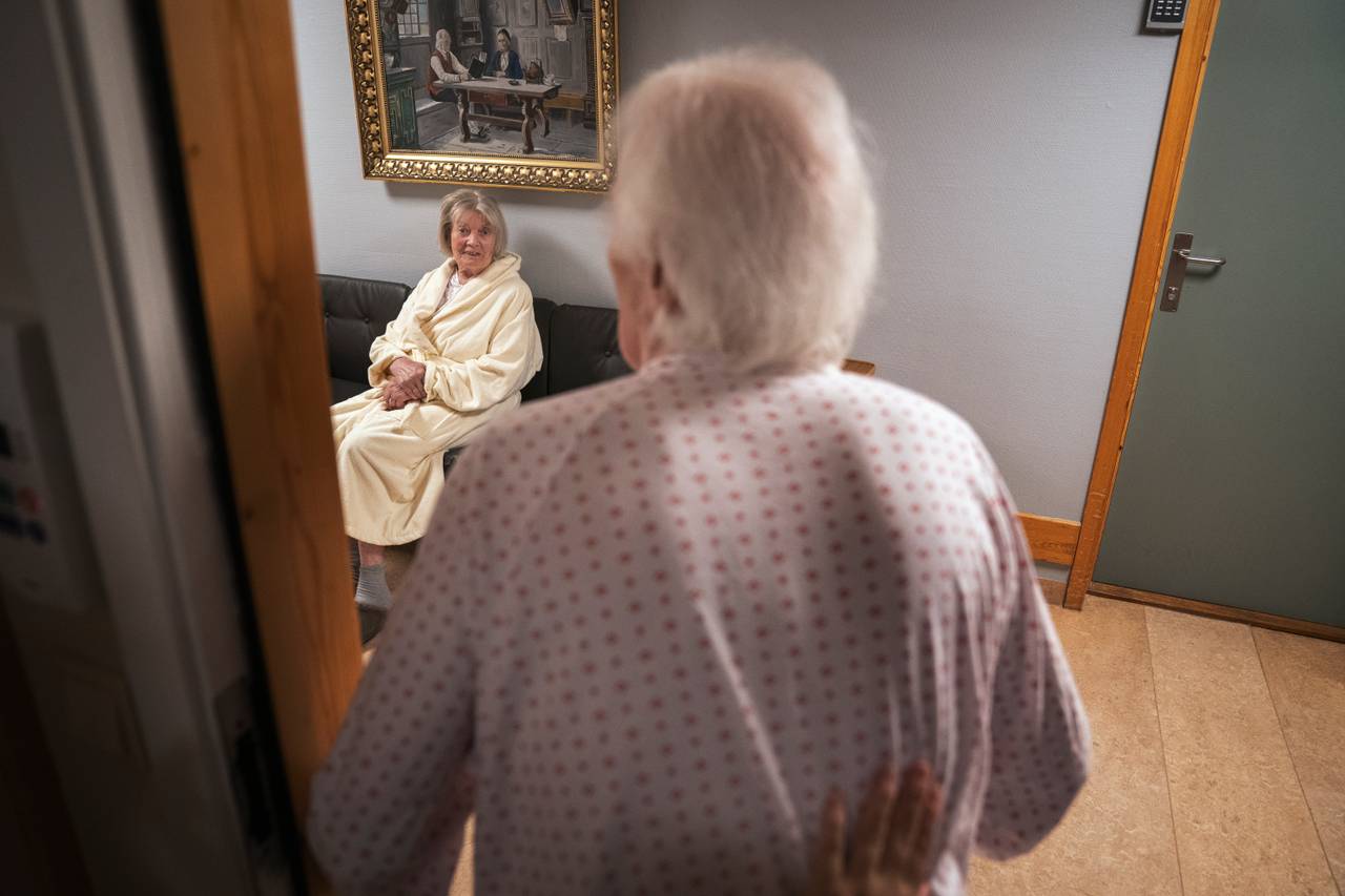 Birger står i døråpningen og møter blikket til Randi, som sitter i sofaen i gangen utenfor.