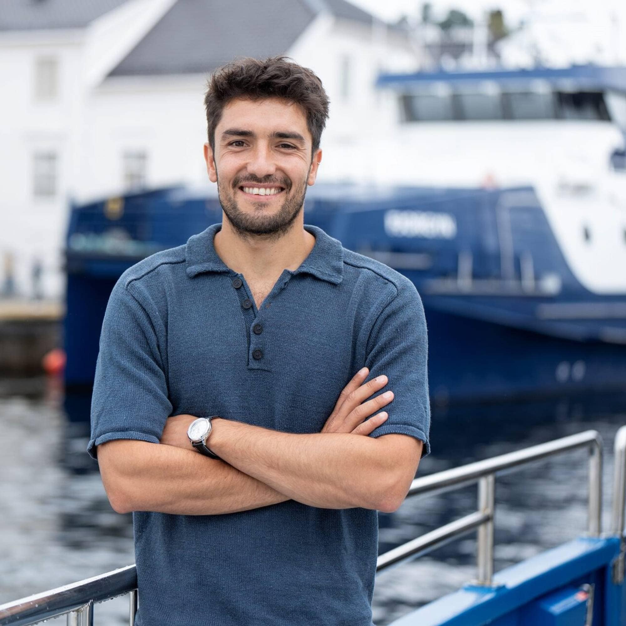 Reber Roald Iversen i Maritime Clean Tech, står smilande med sjø, kai, kurtigbåt og eit kvitt hus i bakgrunnen