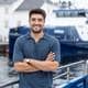 Maritime Clean Tech Reber Roald Iversen i Maritime Clean Tech, står smilande med sjø, kai, kurtigbåt og eit kvitt hus i bakgrunnen