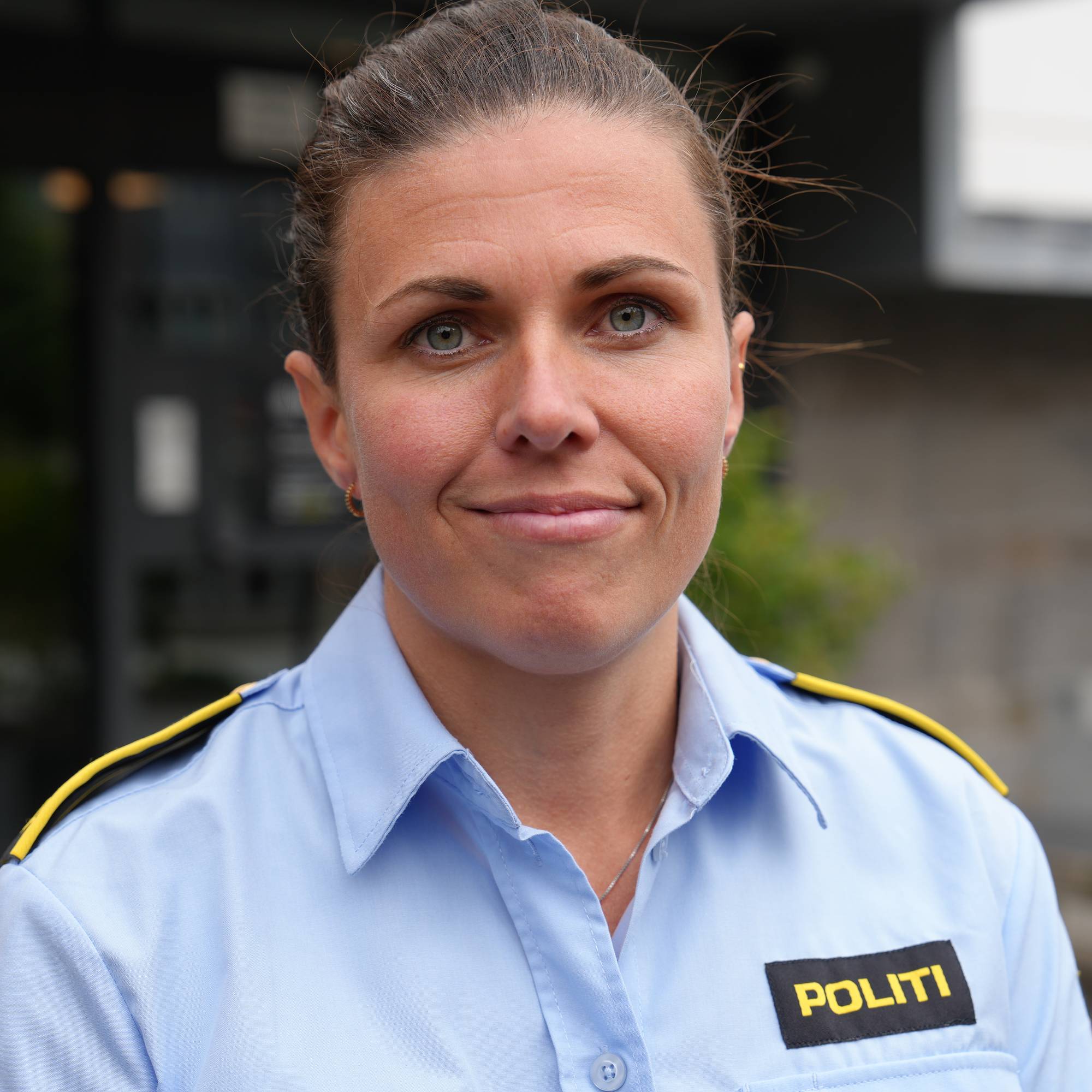 Politiadvokat med blå kortermet uniform ser inn i kamera.