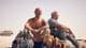 Foto: Fidalgo Filmdistribusjon To menn og en hund sitter i ørkenen.