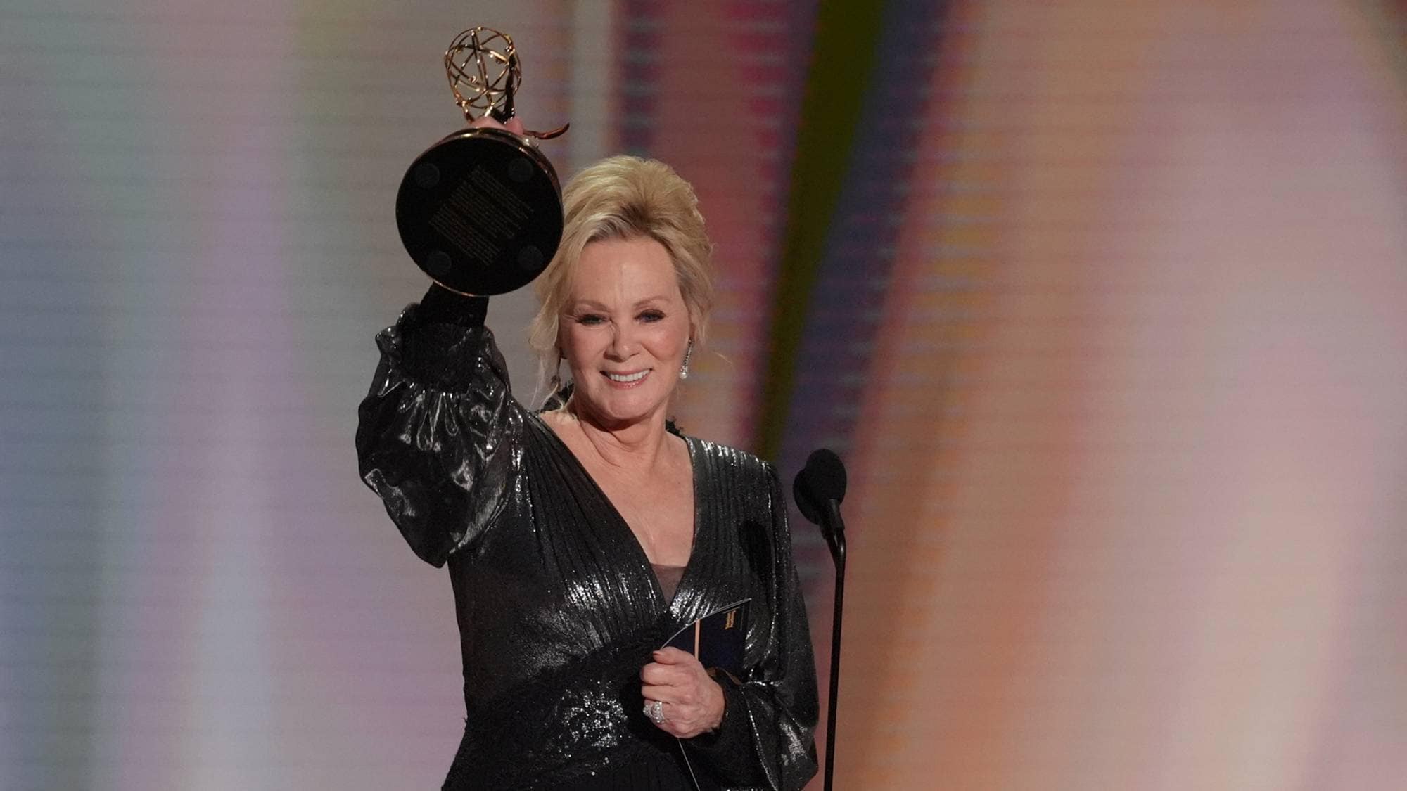 Jean Smart holder opp en Emmy-statuett på en scene under en prisutdeling. (Bildebeskrivelsen er laget av en KI-tjeneste)