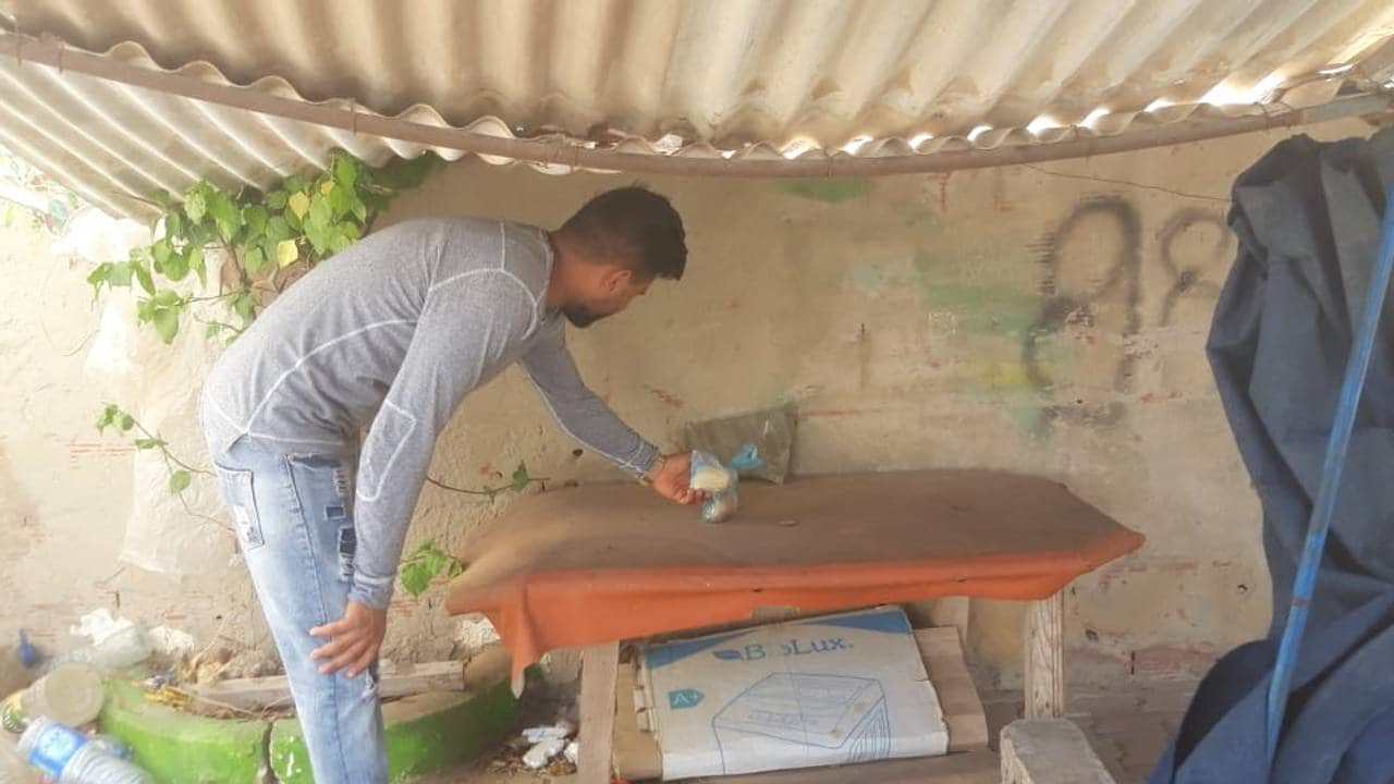 Ahmed, a friend of Ibram, places a plastic bottle on the table of the kiosk where Ir  bram worked. 