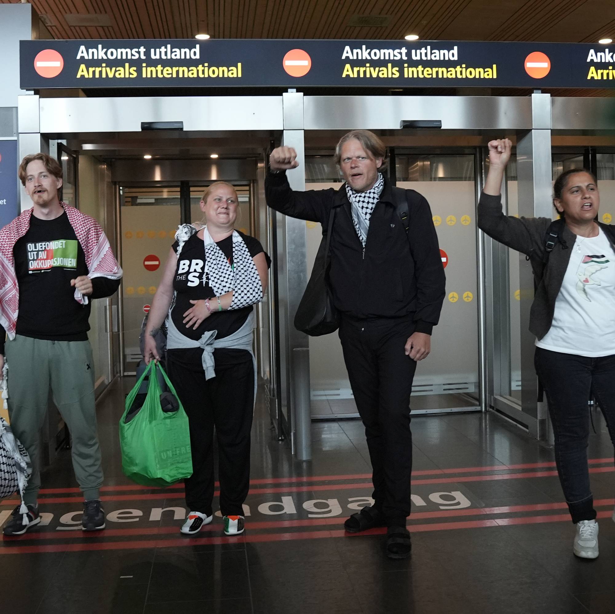 Fire aktivister står i ankomsthallen på Gardermoen