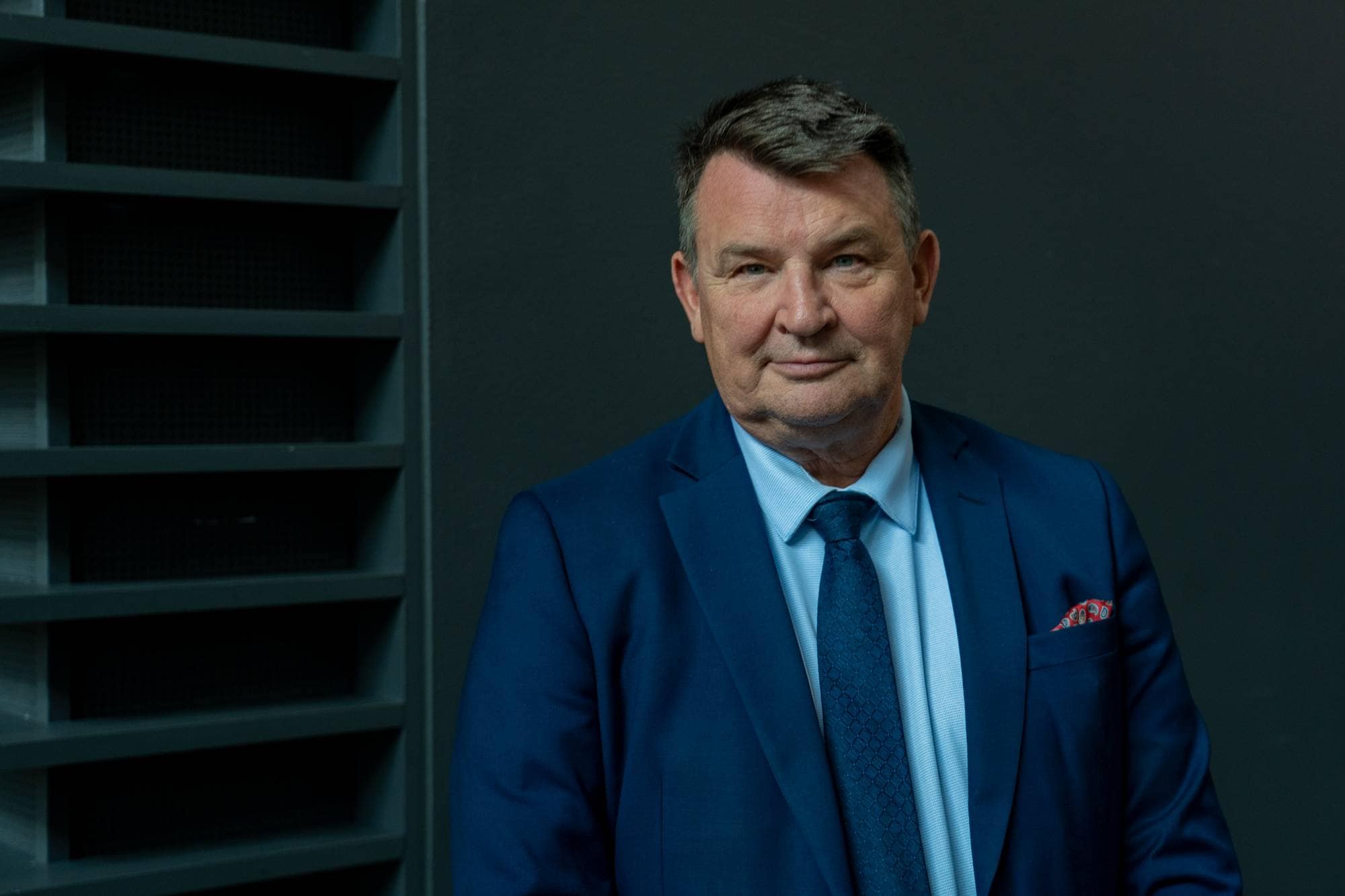 en mann med brunt hår og blå dress ser rett i kamera