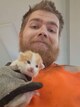 Niklas Forslund Mann med oransje genser holder en liten kattunge